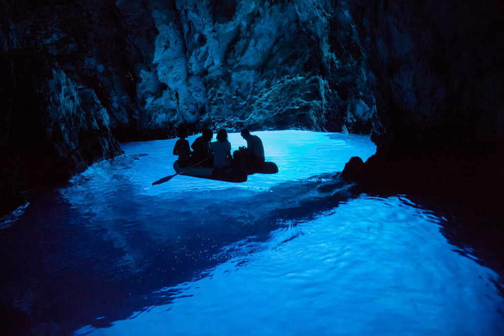 Люди на лодке в пещере с голубой водой.