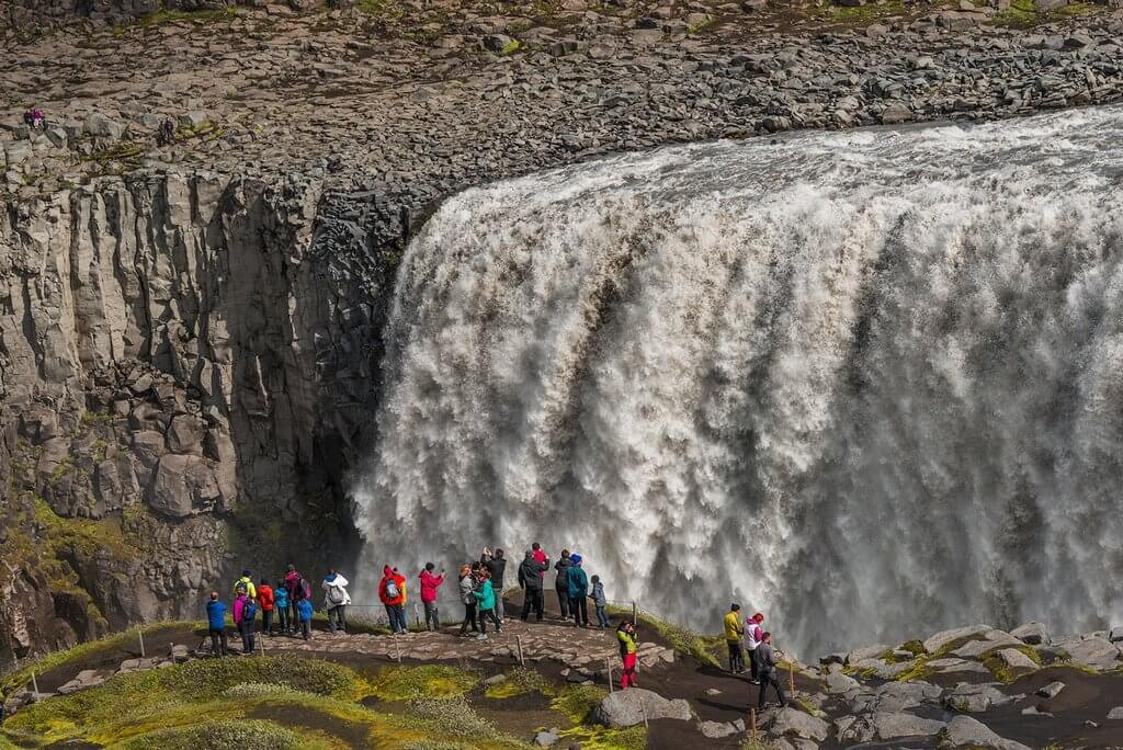 Туристы смотрят на мощный поток воды.