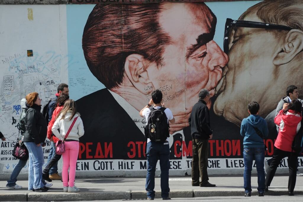 Туристы рассматривают граффити на Берлинской стене.