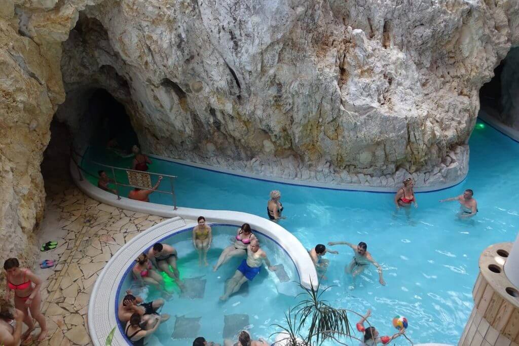 Люди отдыхают в термальном бассейне внутри пещеры.