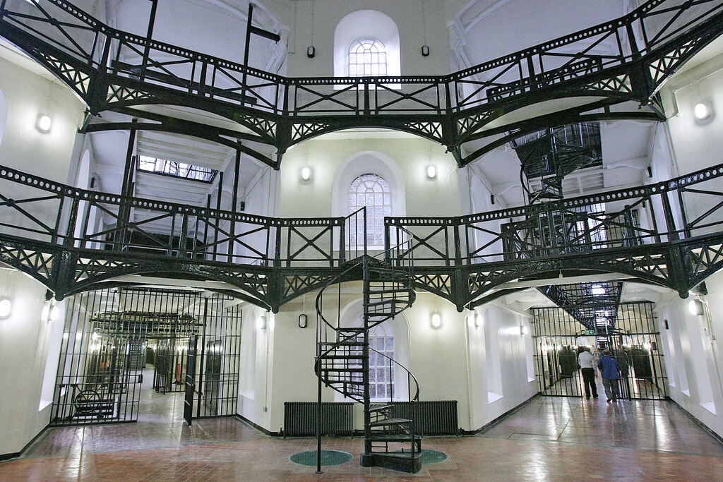 Внутреннее помещение тюрьмы, коридоры и металлические лестницы.