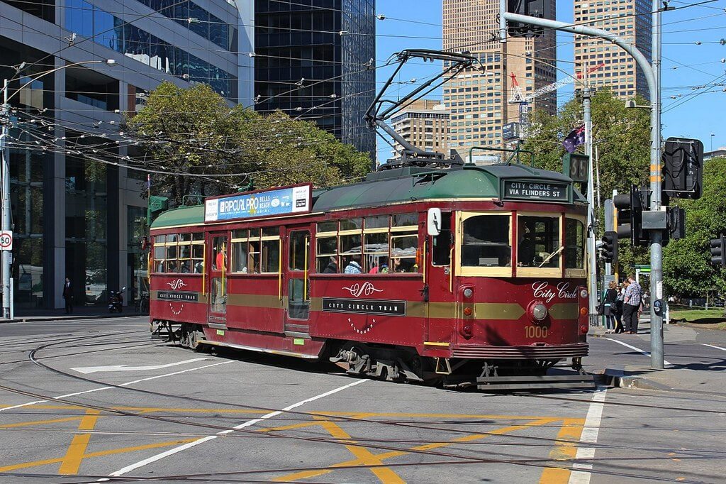 Старый, красный трамвай едет по улице.