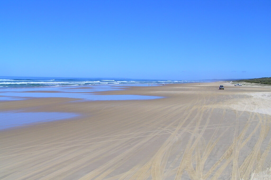 Большой, широкий пляж с белым песком.