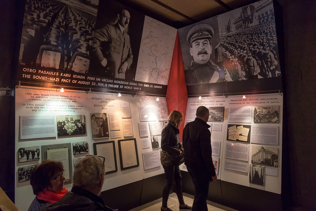 Посетители музея изучают архивные документы. Большие фотографии Гитлера и Сталина.