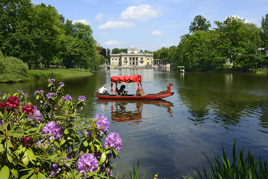 Лодка с туристами в парке на красивом озере на фоне дворца.